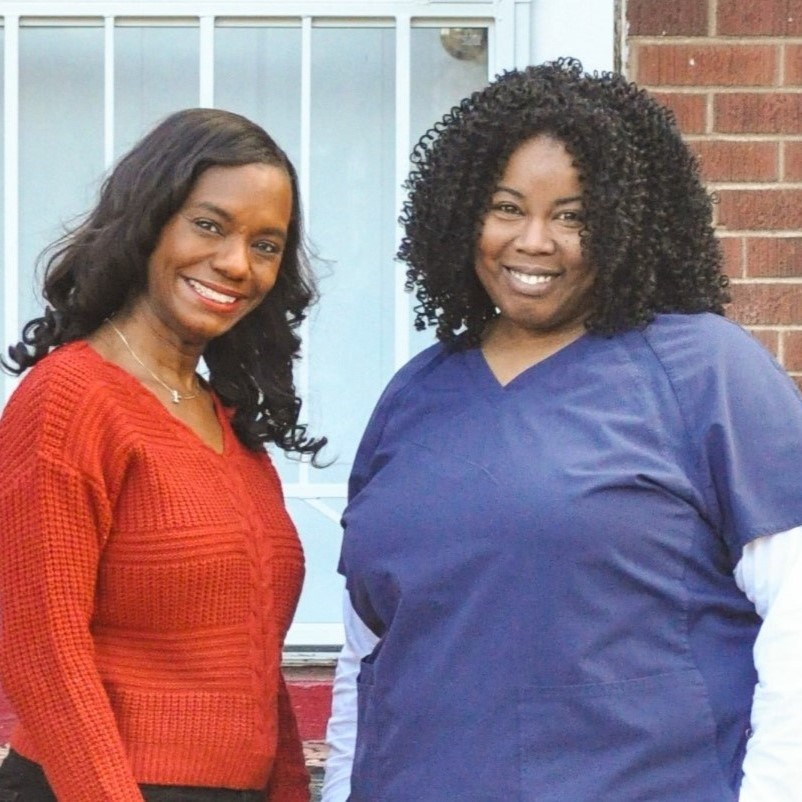 two people smiling while standing in front of a porch of a house