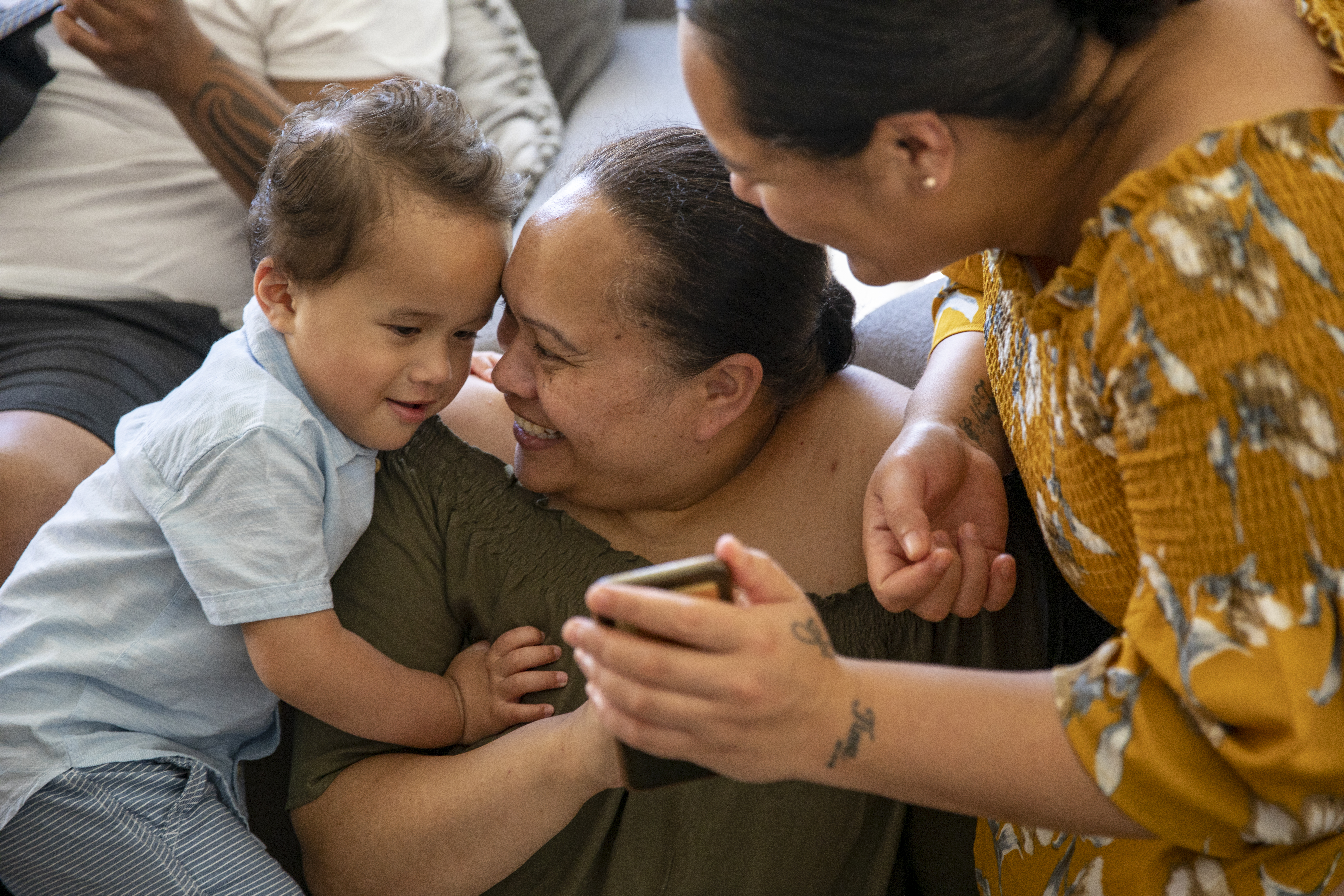 Pacific Islander Family showing a phone to a baby while smiling 